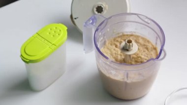 Kadın blender rendelenmiş sebze ve diğer maddeler ile tuz ekler.