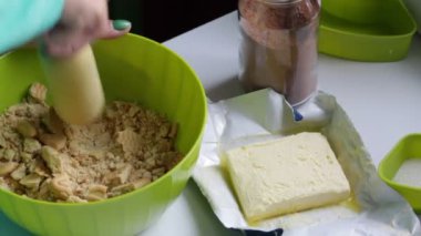 Bir kadın bir oklava ile bisküvi parçalar. Kakao ve bisküvi çikolata tatlılar hazırlanması. Bir maddeler geçerli. Bisküvi, kakao, tereyağı ve şeker kapsayıcılarında.
