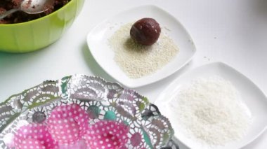 Bir kadın susam bir toz içinde bir karışımı şekerler için gelen topları alır. Kakao ve bisküvi çikolata tatlılar hazırlanması