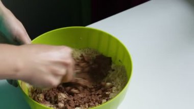 Bir kadın, kakao, şeker, tereyağı, süt ve ezilmiş bir çerez karıştırma. Kakao ve bisküvi çikolata tatlılar hazırlanması.