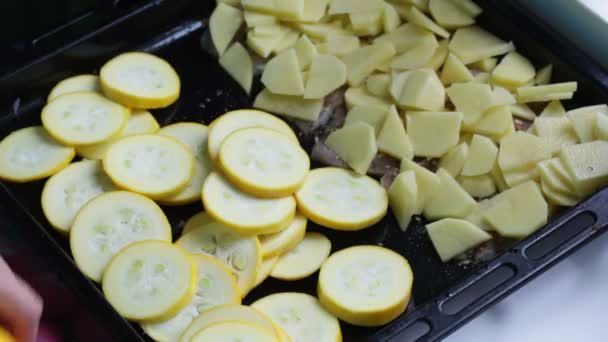 Eine Frau Legt Eine Zucchini Auf Ein Backblech Mit Kartoffeln — Stockvideo