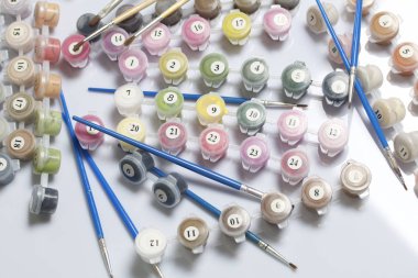 Kapları boyalar ve farklı boyutlarda fırçalar ile numaralandırılmış. Numaraları ile boyama için. Beyaz bir arka plan üzerine döktüm.