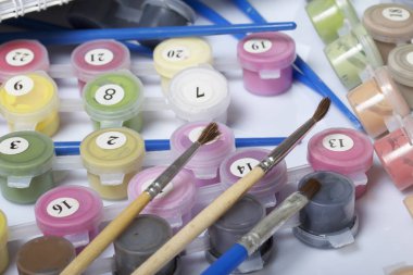 Kapları boyalar ve farklı boyutlarda fırçalar ile numaralandırılmış. Numaraları ile boyama için. Beyaz bir arka plan üzerine döktüm.