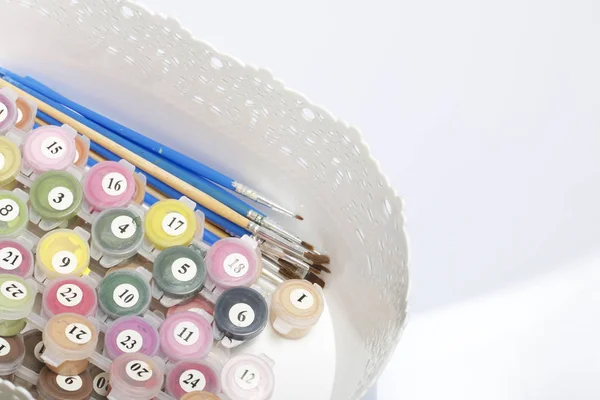 Kapları boyalar ve farklı boyutlarda fırçalar ile numaralandırılmış. Numaraları çizerek için. Beyaz zemin üzerinde bir kapta.