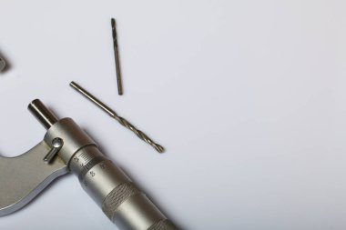 Dış ölçüler ve 25-50 mm ölçüm aralığı için mikrometre ile dairesel bir ölçek. İki matkap. Beyaz bir arka plan üzerinde.