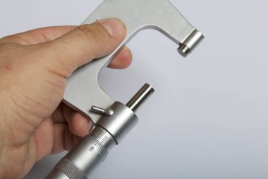 Dış ölçüler ve 25-50 mm ölçüm aralığı için mikrometre ile dairesel bir ölçek. Adamın elinde. Beyaz bir arka plan üzerinde.