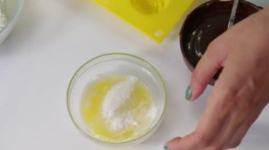 Araçlar ve sırlı curds yapmak için malzemeler. Onlar masada yerleştirilir. Bir kadın şeker erimiş tereyağı ile karıştırma