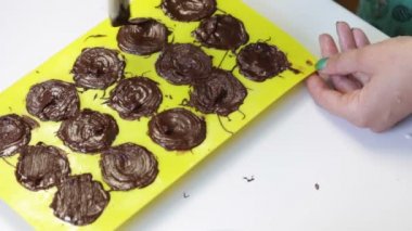 Kadın lor kitle ile eritilmiş çikolata bulaşmış bir formu doldurur. Yanındaki masa yemek pişirmek için unsurlarıdır.