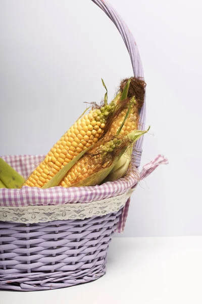 新しい作物 トウモロコシの穂軸は 籐のバスケットにあります 白い背景に — ストック写真