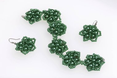 Küpe ve bilezik el yapımı. İğne işi evde. Boncuk takı. Yeşil renkli. Beyaz bir arka plan üzerinde.