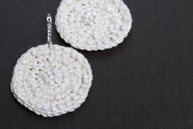 Nakış boncuk dan ile küpe örme. Beyaz renk. El yapımı. Karanlık bir arka plan üzerinde.