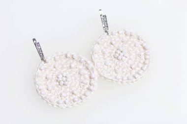 Nakış boncuk dan ile küpe örme. Beyaz renk. El yapımı. Beyaz bir arka plan üzerinde.