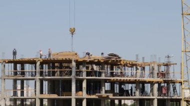 Beton inşaat yapı çerçeve yaptı. İşçiler üst düzey hareket ediyor. Bir kule vinç çalışır.