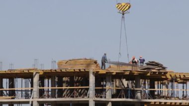 Beton inşaat yapı çerçeve yaptı. İşçiler üst düzey hareket ediyor. Bir kule vinç çalışır.