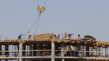 Beton inşaat yapı çerçeve yaptı. İşçiler üst düzey hareket ediyor. Bir kule vinç çalışır.