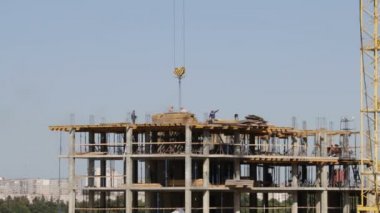 Beton inşaat yapı çerçeve yaptı. İnşaat işçileri hareket ediyor. Bir kule vinç çalışır.