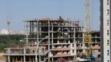 Beton inşaat yapı çerçeve yaptı. İnşaat işçileri hareket ediyor. Bir kule vinç çalışır.