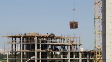 Beton inşaat yapı çerçeve yaptı. İnşaat işçileri hareket ediyor. Kule Vinç Yük taşır.