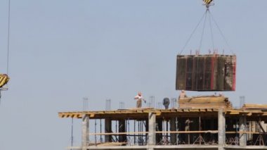 Beton inşaat yapı çerçeve yaptı. İnşaat işçileri hareket ediyor. Kule Vinç Yük taşır.