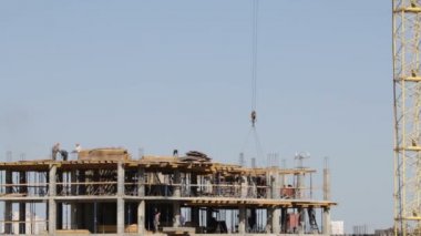 Beton inşaat yapı çerçeve yaptı. İnşaat işçileri hareket ediyor. Kule Vinç Yük düşürür.