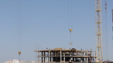 Beton inşaat yapı çerçeve yaptı. İnşaat işçileri hareket ediyor. Kule Vinç Yük düşürür.