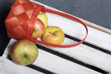 Hasır sepet içinde olgunlaşmış aromatik elma. Panoları dışarı çaldı bir ahşap kutu üzerinde yer alan.