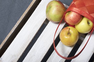 Hasır sepet içinde olgunlaşmış aromatik elma. Panoları dışarı çaldı bir ahşap kutu üzerinde yer alan.