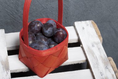 Hasır sepet içinde olgunlaşmış kokulu Erik. Panoları dışarı çaldı bir ahşap kutu üzerinde yer alan.