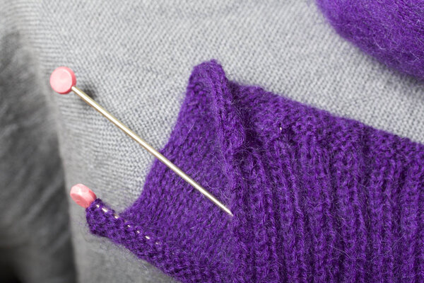 Вязание стальными вязальными спицами. Шар из фиолетовых ниток и стальных вязальных иголок в незаконченном вязании
.