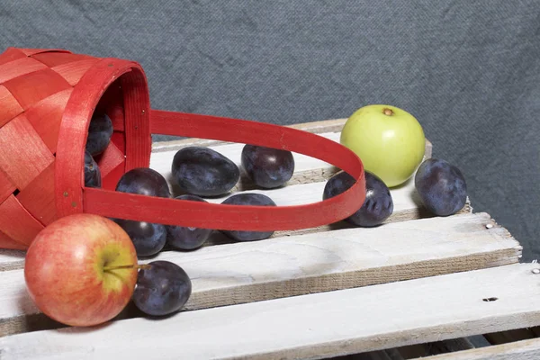 Olgun güzel kokulu Erik ve elma bir hasır sepet dışarı ufalanmış. Panoları dışarı çaldı bir ahşap kutu üzerinde yer alan.