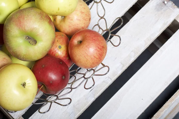 Ripe aromatic apples in a steel basket. Located on a wooden box, knocked out of the boards.