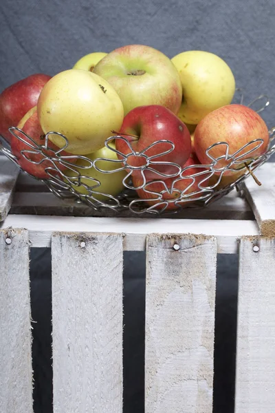 Ripe aromatic apples in a steel basket. Located on a wooden box, knocked out of the boards.