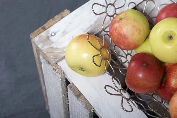 Ripe aromatic apples in a steel basket. Located on a wooden box, knocked out of the boards.