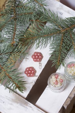 Mavi Ladin dallarda panoları, beyaz boyalı bir ahşap kutu. Yakında orada küpe ve kavanoz boncuklar ile.