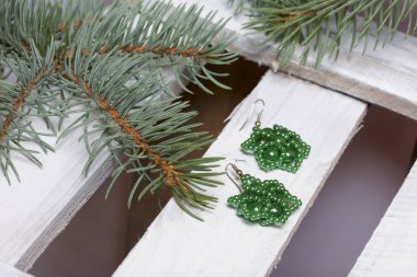 Mavi Ladin dallarda panoları, beyaz boyalı bir ahşap kutu. Yakında orada küpe ve kavanoz boncuklar ile.