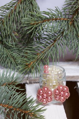 Mavi Ladin dallarda panoları, beyaz boyalı bir ahşap kutu. Yakında orada küpe ve kavanoz boncuklar ile.