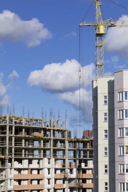 Kule vinç bir bina inşaat betonarme bir çerçeve ile. Mavi bir gökyüzü güneşli.