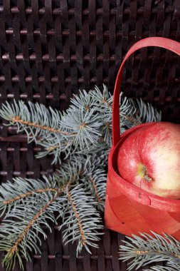 Mavi Ladin ve sepet içinde olgunlaşmış kokulu elma dalı. Bir hasır asma arka planı.