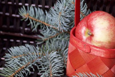 Mavi Ladin ve sepet içinde olgunlaşmış kokulu elma dalı. Bir hasır asma arka planı.