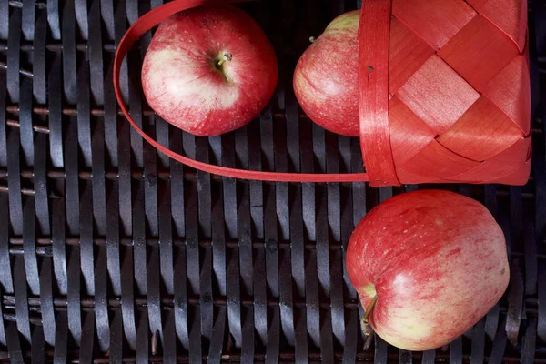 Olgun aromatik elma kırmızı hasır sepetin içinde. Hasır bir hasır sepet arka planı.