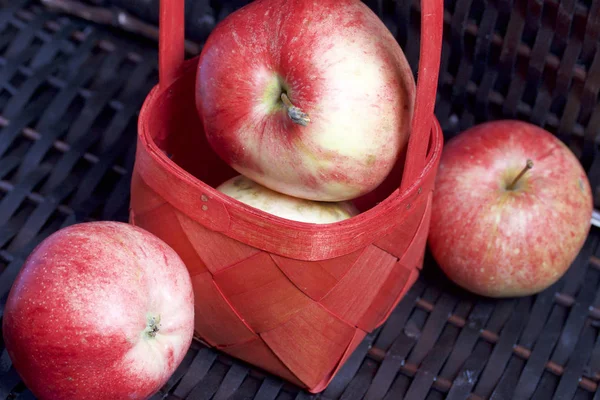 Olgun aromatik elma kırmızı hasır sepetin içinde. Hasır bir hasır sepet arka planı.
