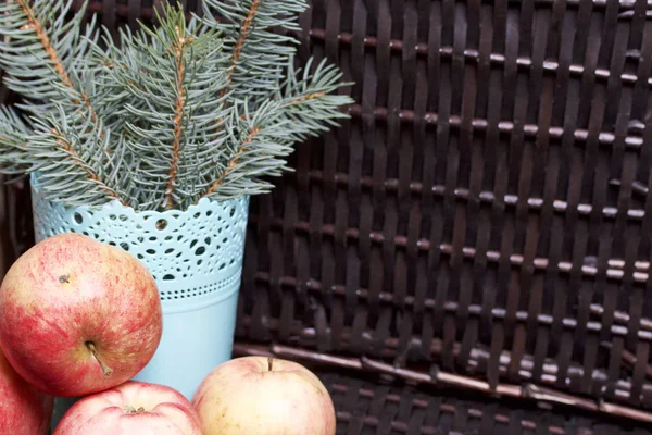 Mavi Ladin ve olgunlaşmış kokulu elma dalı. Hasır bir hasır sepet arka planı.