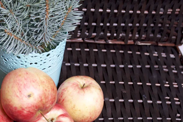 Mavi Ladin ve olgunlaşmış kokulu elma dalı. Hasır bir hasır sepet arka planı.
