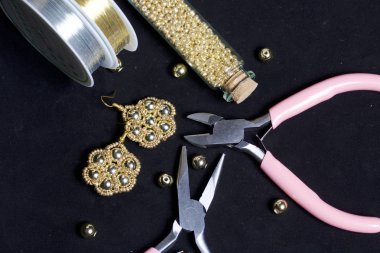 Boncuk takı. DIY Takı. Gerekli aksesuarları. Boncuk ve hazır küpe. Araçlar ve armatürleri. Siyah bir arka plan üzerinde.