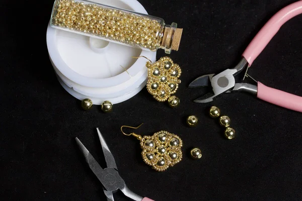 Boncuk takı. DIY Takı. Gerekli aksesuarları. Boncuk ve hazır küpe. Araçlar ve armatürleri. Siyah bir arka plan üzerinde.