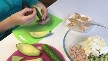 Tablo yüzeyinde lor olan kütle ve sebze yemek pişirmek için. Bir avokado bir kadın soyma.