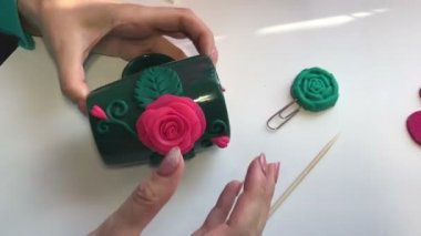 El sanatları polimer Clay. Bir kadın bir zamklı polimer kil çiçek bir fincan için yapışır. Sonraki masaya polimer kil Dekoratif unsurları vardır. Polimer kil yapılan sıva ile dekore edilmiş kupa.