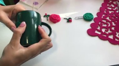 El sanatları polimer Clay. Bir kadın bir fincan için bir parça polimer kil yapışır. Sonraki masaya polimer kil Dekoratif unsurları vardır. Polimer kil yapılan sıva ile dekore edilmiş kupa.