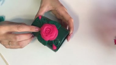 El sanatları polimer Clay. Kadın kupasına yapıştırılmış polimer kil yapılmış bir dekoratif unsur düzeltiyor. Sonraki masaya polimer kil Dekoratif unsurları vardır.