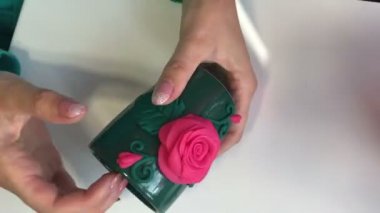 El sanatları polimer Clay. Kadın bir ahşap şiş ile polimer kil kupasına yapıştırılmış yapılmış bir dekoratif unsur düzeltiyor. Sonraki masaya polimer kil Dekoratif unsurları vardır